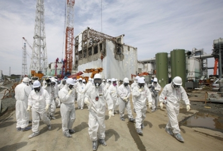 Para pekerja di Tokyo Electric Power Co (TEPCO), mengenakan pakaian pelindung dan masker, sedang berjalan di depan Reaktor Nulir Nomor 4 di Fukushima Daiichi. Reaktor ini mengalami kebocoran akibat tsunami. (Photo : Reuters)